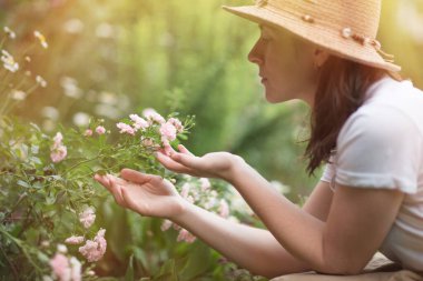 Süs bahçesinde çiçek açan çalılar. Şapkalı kız Park 'ın çiçeklerine bakıyor. Bahçe işleri ve peyzaj işleri