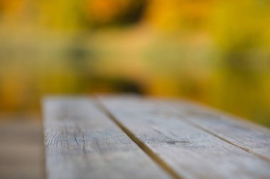 Parktaki ahşap bank, sarı sonbahar yapraklarının arka planına karşı.