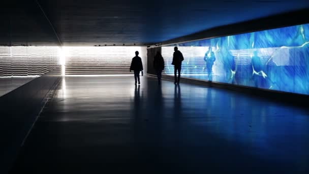 Подземный переход с голубой подсветкой, метро - мимо ходят люди — стоковое видео