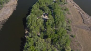 Kuru sarı sazlıklar, yeşil ağaçlar, açık mavi gökyüzü, parlak güneş. Birçok martı dalgalar olmadan sakin suyun üzerinde uçar. Nehrin üzerinde akşam batımı. Sudaki ahşap çardak..