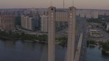 Kiev 'deki Dinyeper nehrinin üzerindeki güney köprüsü. Drone film çekiyor. Akşam güneşinin ışınlarında metal telleri olan beton köprü bulutları delip geçiyor. Geniş nehir ve yüksek binalar.