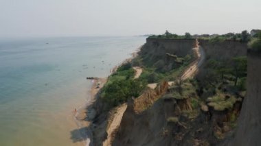 Sanzheyka köyü yakınlarındaki Karadeniz 'in sarp kıyısı kuş bakışı. Deniz kıyısındaki çamurlu uçurum. Kurumuş çimenler ve deniz kenarındaki yeşil ağaçlar..