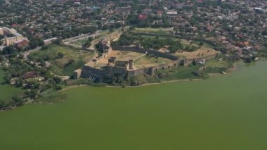 Kuşbakışı Belgorod-Dnestrovskaya kalesi. Ukrayna 'nın en büyük kalesi Dinyester Nehri üzerindedir. Yeşil çiçekli su ve kalenin beyaz taş duvarları.
