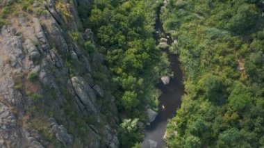 Mertvovod nehrinin Aktovsky kanyonu kuş bakışı. Beyaz taş atan dron, yeşil ağaçlar, bulutlu mavi gökyüzü, kanyonun dibinde sığ bir nehir akıyor. Etrafında sarı kurumuş bir çayır var..
