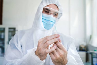 Koruyucu gözlüklü erkek cerrah ya da doktorun portresi ve elinde şırınga, ilaç ya da aşı bulunan maske dozu alıyor - sağlık sigortası ve covid-19 konsepti