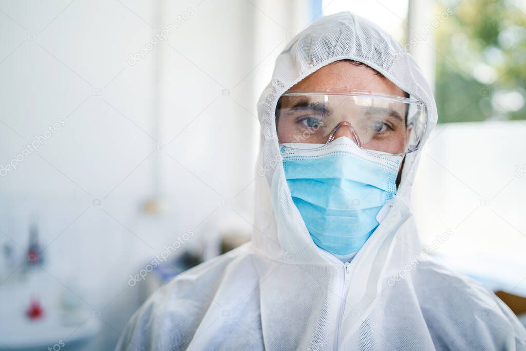 Front view portrait of young male caucasian doctor medic wearing protective suit eyeglasses and surgical mask at hospital - Safety protection paramedic during covid-19 pandemic - healthcare concept