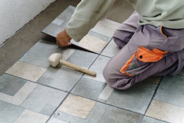 Gündüzleri balkona ya da terasa seramik fayanslar döşeyen, inşaat endüstrisi konsepti fotokopi alanı olan yapışkan çimento üzerine bilinmeyen usta zanaatkârın ellerine yakın durun.