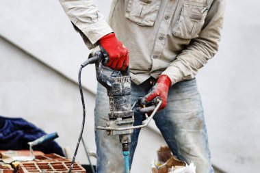 İnşaat alanında tutkal hazırlamak için el elektrikli matkabı kullanarak kimliği belirsiz bir adamın göbeğine yaklaş.