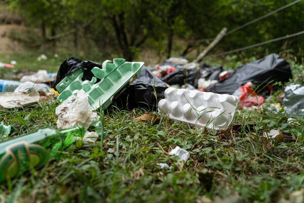 Pollution in nature - garbage thrown on the field covering grass - trash in the countryside on illegal dump