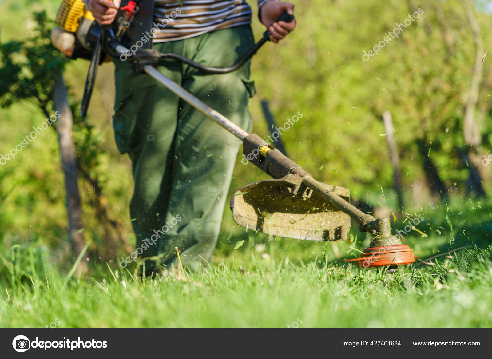 Jardinero sonriente sosteniendo cortasetos de gasolina al aire