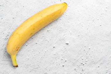 Parlak mermer masada, üzerinde fotokopi alanı olan olgun sarı bir muz.