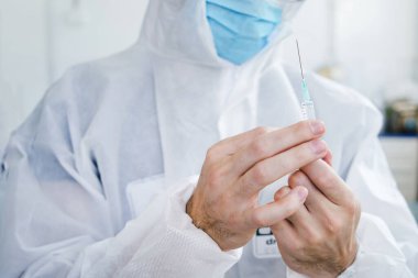 Bilinmeyen beyaz erkek doktorun ellerinde aşı dozuyla şırınga tutarken yaklaş - yeni normal konsept tıp çalışanı salgının yayılmasını önlemek için aşıya hazır - uzay görüşünü kopyala