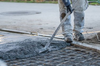 Gün içinde inşaat alanında yere beton harç döken kimliği belirsiz bir işçinin göbeğine yaklaş.