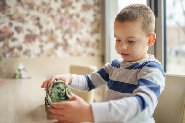 Pequeño Niño Caucásico Jugando Mesa Sentado Frente Ventana Sosteniendo Juguete — Foto de Stock