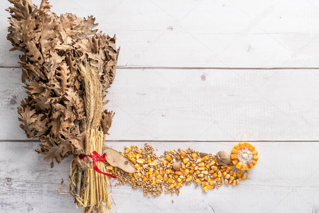 Top view on oak branches with wheat and corn seed and nuts on wooden table with copy space - orthodox christmas badnjak concept