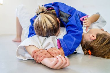 Kenar kontrol 100 kilo, amerikan boyun eğme judo bjj Brezilya jiu-jitsu eğitimi iki kadın dövüşçü kimono giyerek antrenman yapıyor.
