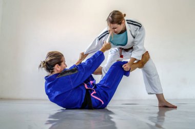 Brezilya jiu jitsu bjj eğitiminde De la riva gardiyanı. İki bayan sporcu dövüşçüyü çalıştırıyor. Yarışmada ileri düzey siyah ve kahverengi kuşak teknikleri uyguluyorlar.