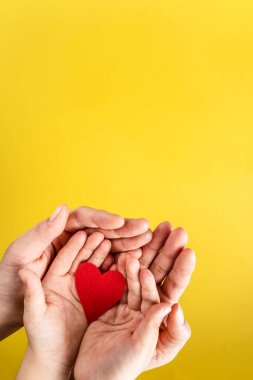 Anne ve oğulun avuç içlerindeki kırmızı hardal - modern soyut sarı arka plan üzerinde kırmızı harp şekilli beyaz kadın ve çocuk - sevgi koruma anneliği ve aile kavramı
