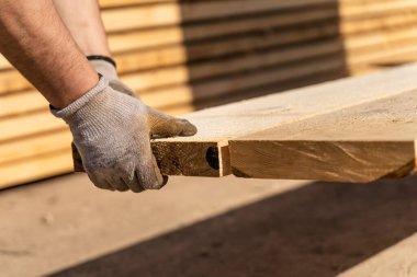 Güneşli bir günde depoda fotokopi uzayı ile kereste toplayan Kafkasyalı inşaat işçisinin eldiveni ile yakın çekim yapın.