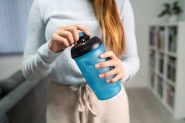 Elinde takviye malzemesi tutan kimliği belirsiz beyaz kadının ellerini kapat. Evde dikilirken ya da ön görüntüyü açarken ya da kapatırken.
