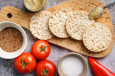 Sehpada gevrek pirinç kekleri ve domates sebzeleri ve masada susam tohumları. Sağlıklı vejetaryen ya da vejetaryen kahvaltısı glütensiz.