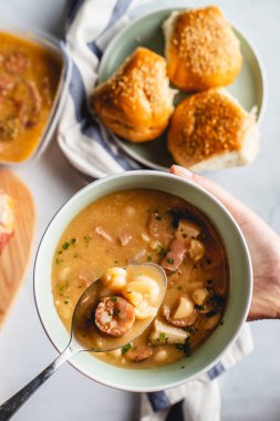 Böbrek fasulyesi çorbası füme sosis ve domuz pastırması masada.
