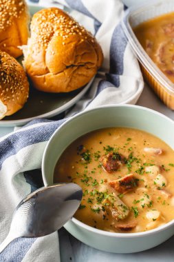 Böbrek fasulyesi çorbası füme sosis ve domuz pastırması masada.