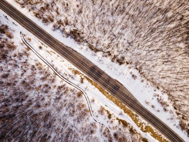 Sırbistan 'ın Knjazevac kenti yakınlarında kış günü beyaz karla kaplı dağlık alanda ağaçlar ve orman boyunca yol üzerindeki yüksek açılı drone görüntüsü - seyahat yolculuğu ve tatil kavramı
