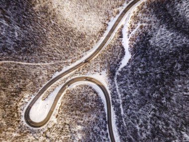 Sırbistan 'ın Knjazevac kenti yakınlarında kış günü beyaz karla kaplı dağ sırasındaki ağaçlar ve ormanlar boyunca kıvrımlı yılan yolundaki yüksek açılı hava aracı görüntüsü - Seyahat yolculuğu konsepti