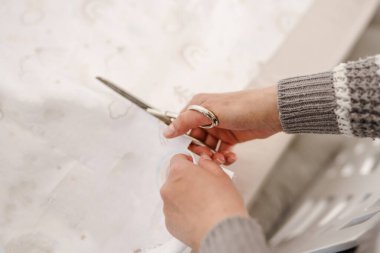 Ev veya stüdyoda elinde makas tutan, tekstil kesen, hobi ve terzilik konsepti fotokopi alanının üst görünümü olan, kimliği belirsiz beyaz kadının ellerine yaklaş.