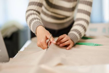 Bilinmeyen beyaz kadının elinde makas, evinde ya da stüdyosunda tekstil kesen ellerine yaklaş. Hobi ve terzilik konsepti fotokopi alanı.