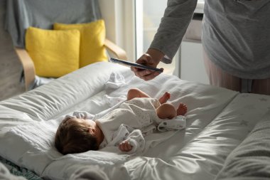Bilinmeyen beyaz bir anne cep telefonu kullanıyor. Yeni doğmuş bebeğinin ya da kızının fotoğraflarını çekiyor. Gündüzleri yatakta yatıyor.