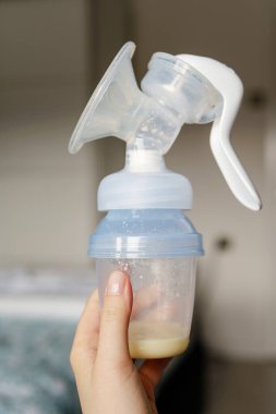 Yeni doğan bebeklerin beslenmesi için meme pompası tutan beyaz bir kadın ve genç bir anne var.