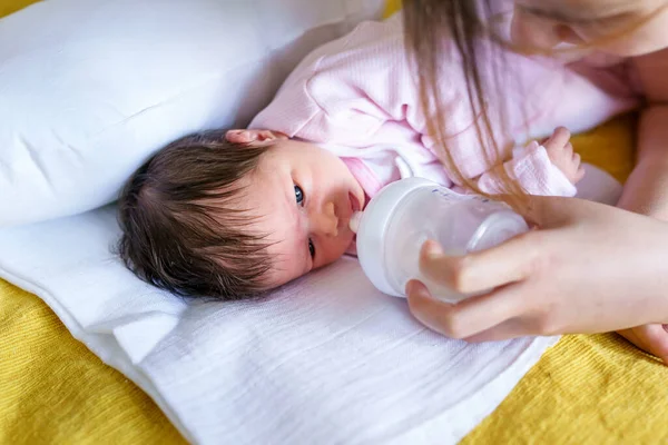 人工的なミルクの公式食品 健康と栄養子育てと新生児の健康的な食品の概念を供給するボトルから飲むベッドの上で彼女の母親によって横たわっている2週間の白人の赤ちゃんの幼児に閉じます — ストック写真