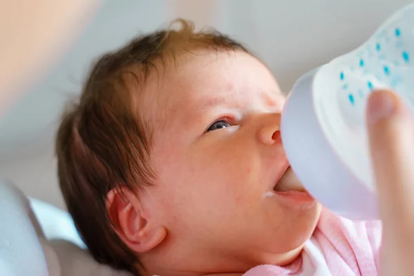 one week old caucasian baby bottle feeding artificial milk close up