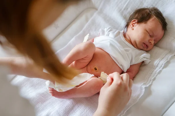 Annesi bebek bezi değiştirirken, beyaz bebek uykusunun en üst görüntüsü ve yeni doğan bebek bezi evde yatakta yatarken - çocukluk çocukluğu ve büyüme konsepti.
