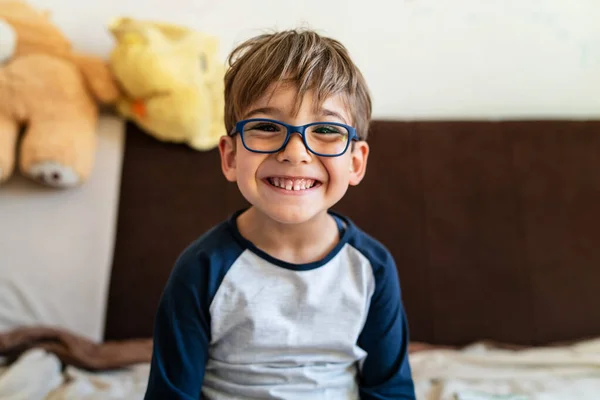 幸せな白人男の子の肖像画で眼鏡をかけて家の中に一日で本物の人々小さな男遊び心のある子供をカメラを見て笑顔 — ストック写真