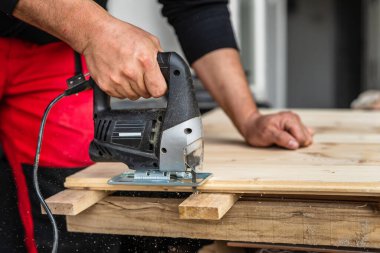 Bilinmeyen bir marangozun elektrikli testereyle çalışıp ahşap testereyle ahşap doğrama konsepti kopyalama alanına yakın çekim