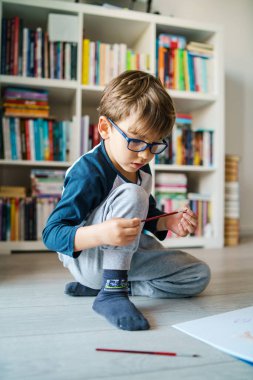 Evinde yerde oynayan dört yaşındaki beyaz çocuk hakkında ön görüş - suluboya resim yaparken boya kullanan küçük bir çocuk sanatsal beceriler geliştiriyor, boş zamanlarını ve yaratıcı eğitimi geliştiriyor.