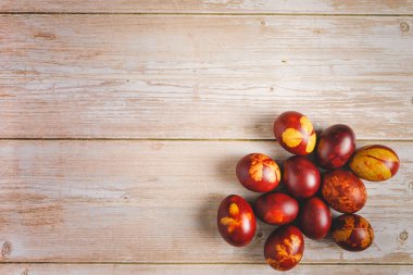 Ahşap zemin üzerine boyanmış Paskalya yumurtalarına düz bir görünüm.