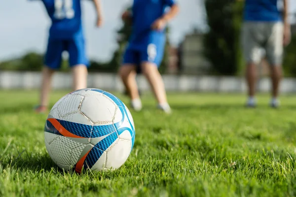 サッカーのトレーニング中にサッカーボールを閉じたり 背景にぼやけた選手と晴れた日にフィールド上の芝生の上でゲーム スポーツのコンセプトコピースペース — ストック写真
