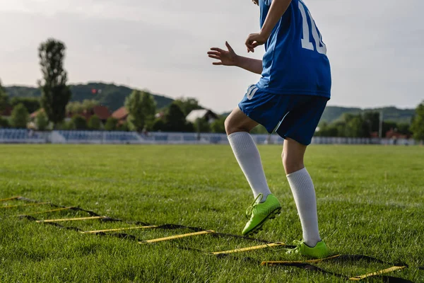 Close up on low section of unknown caucasian child boy training mobility and coordination on the football soccer field using ladder drills and exercise concept copy space