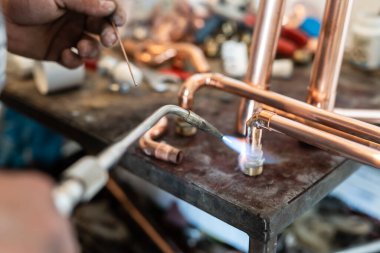 İşyerinde gaz lambası ya da kaynak makinesi kullanan merkezi ısıtma boruları olan bilinmeyen endüstriyel tesisatçıların ellerini kapatın.