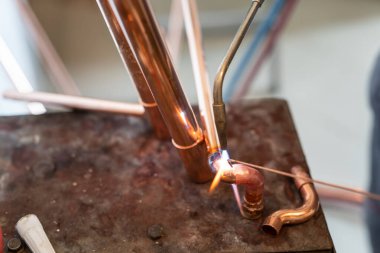 İşyerinde gaz lambası ya da kaynak makinesi kullanan merkezi ısıtma boruları olan bilinmeyen endüstriyel tesisatçıların ellerini kapatın.