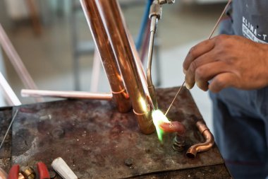 İşyerinde gaz lambası ya da kaynak makinesi kullanan merkezi ısıtma boruları olan bilinmeyen endüstriyel tesisatçıların ellerini kapatın.