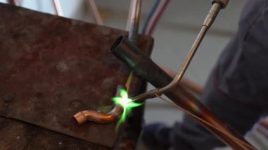 İşyerinde gaz lambası ya da kaynak makinesi kullanan merkezi ısıtma boruları olan bilinmeyen endüstriyel tesisatçıların ellerini kapatın.