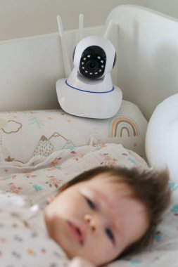 Yatak odasındaki bebek yatağının güvenlik kamerası beşikteki küçük çocuğu uyurken izliyor.
