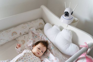 Yatak odasındaki bebek yatağının güvenlik kamerası beşikteki küçük çocuğu uyurken izliyor.