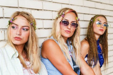 Beyaz tuğla duvarın yanında duran üç güzel beyaz kadın - yaz gününde annesiyle birlikte olan kız ya da kız arkadaşları - gerçek insanlar boş boş boş geziniyor gençlik tasasız konsepti kapatıyorlar