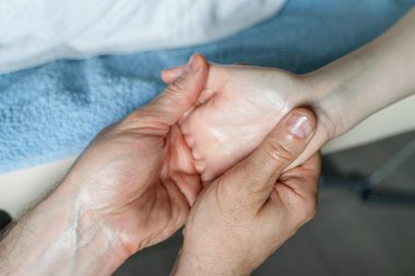Bilinmeyen beyaz erkek terapistin ellerine yaklaş. Masaj yapıyor ve bilinmeyen kadın müşterinin ellerini uzatıyor.